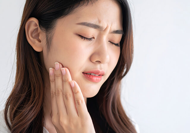 痛そうに頬を押さえている女性